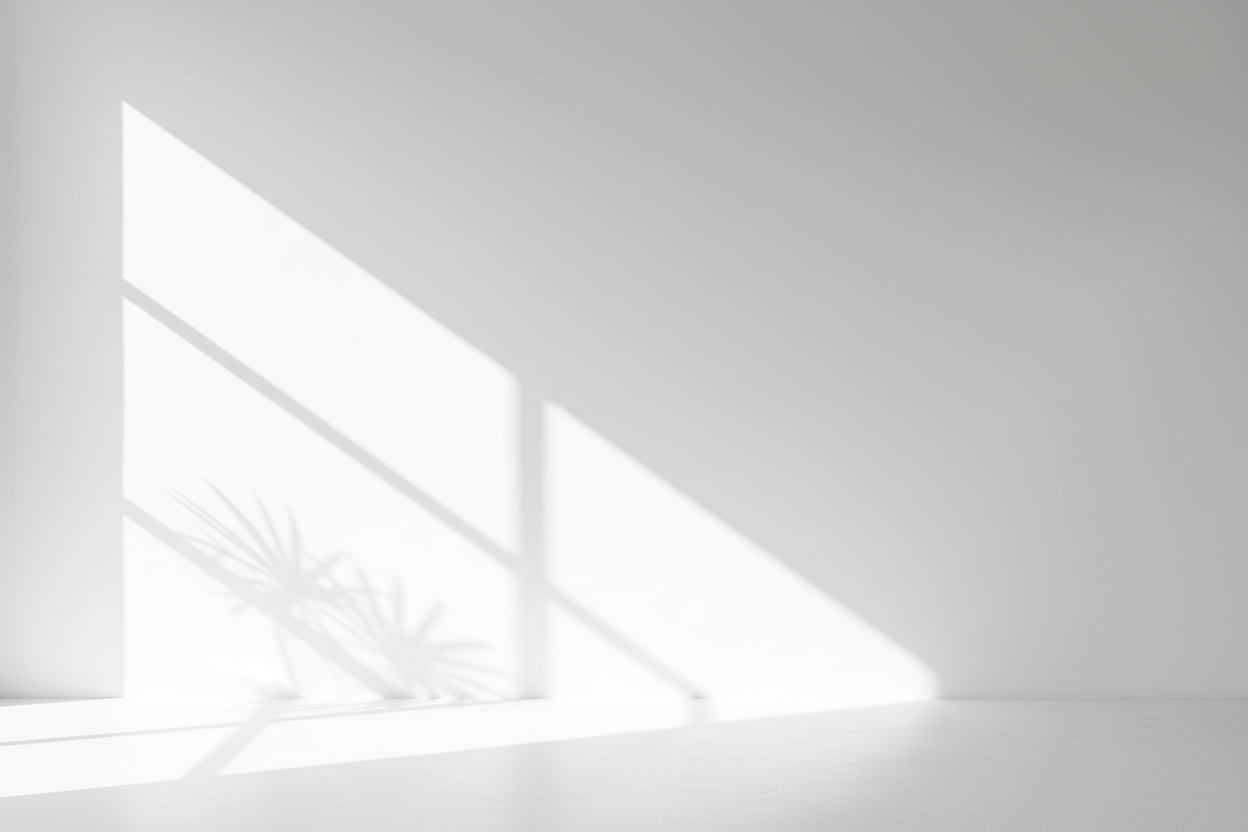 자연광으로 인한 미묘한 그림자 놀이가 있는 깔끔하고 미니멀한 흰색 벽 배경.