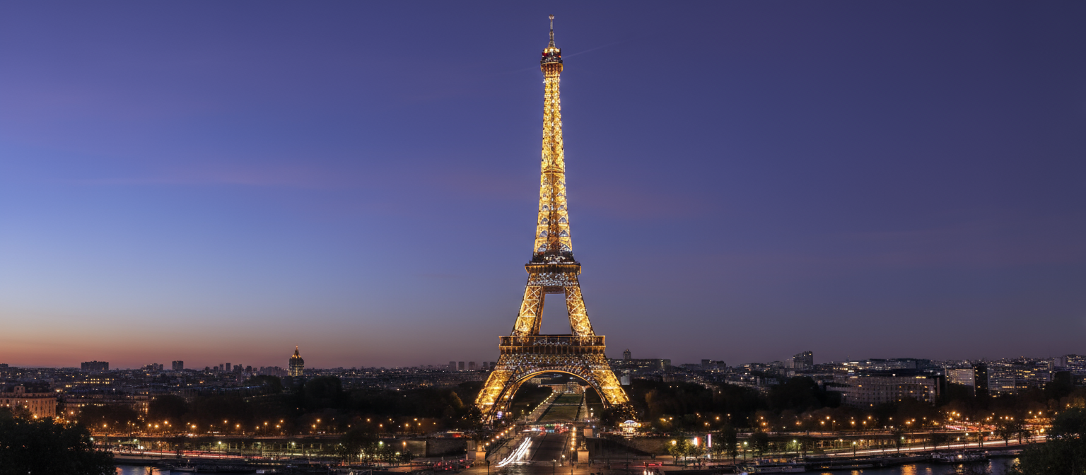 깊은 푸른빛 밤하늘 아래 황금빛 조명으로 반짝이는 파리 에펠탑.