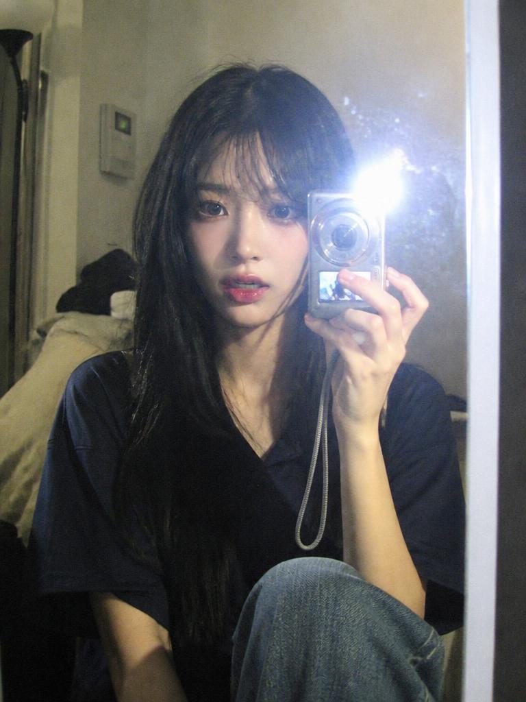 A nostalgic 2000s compact digital camera mirror selfie with flash glare and grain.